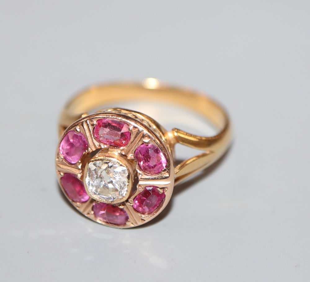 A late 19th/early 20th century yellow metal, ruby and diamond set circular cluster ring, size J, gross 3.8 grams.
